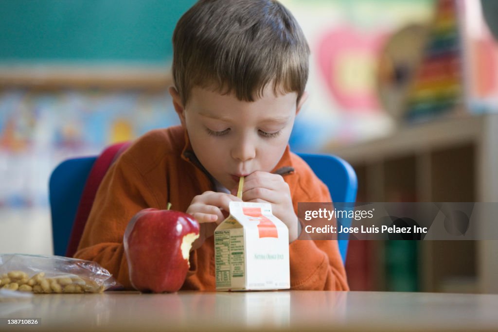 Caucasian boy eating lunch in classroom