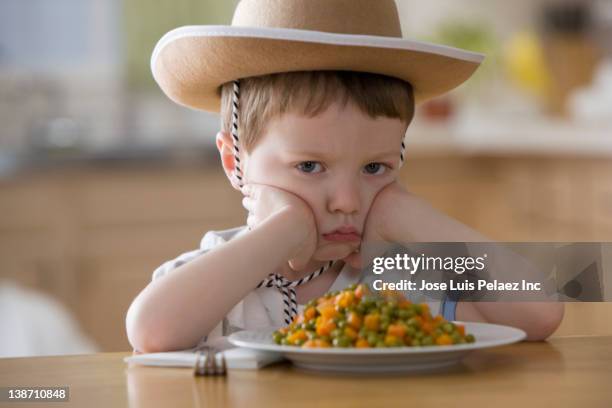 unhappy caucasian boy sitting at dinner table - caprice photos et images de collection