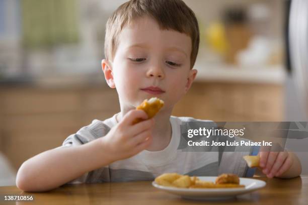 caucasian boy eating chicken nuggets - chicken nugget photos et images de collection