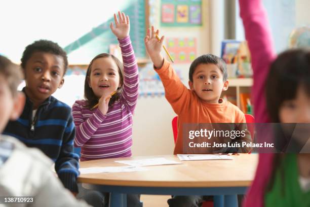 students raising hands in classroom - child school photos et images de collection