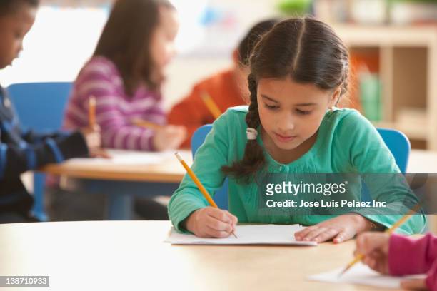 hispanic girl studying in classroom - kinder schreiben stock-fotos und bilder