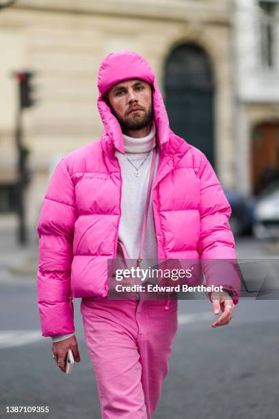 Influencer Karb wears a pink puffy balaclava hat, a white turtleneck pullover, a neon pink puffer jacket, a pink shiny leather crossbody bag from...