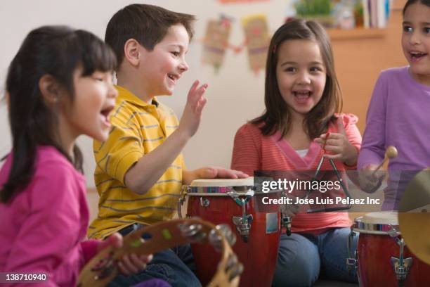 students playing musical instruments in classroom - kids instruments stock-fotos und bilder