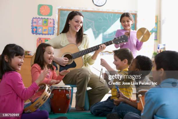 teacher playing guitar for students in classroom - percussion instrument stock pictures, royalty-free photos & images