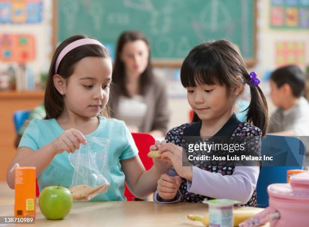 girls eating lunch together in classroom - vrijgevigheid stockfoto's en -beelden
