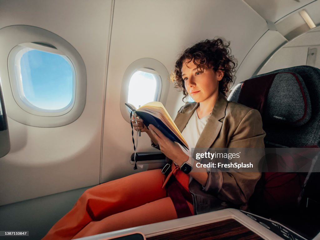 A Beautiful Businesswoman Reading Her Notes While Travelling By Plane