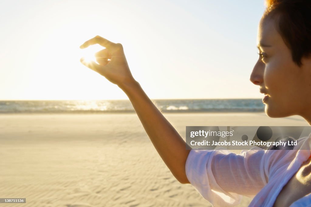 Mixed race woman pinching sun on beach