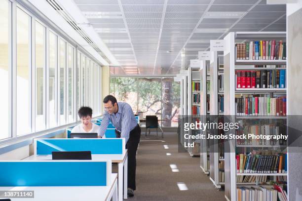 teacher helping student in library - university of western australia stock pictures, royalty-free photos & images