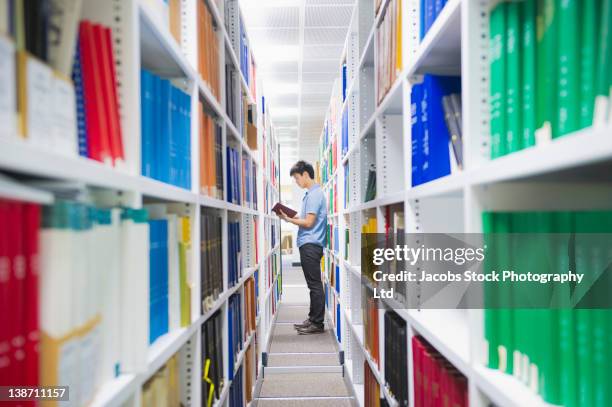 chinese man holding book in library - university student australia stock pictures, royalty-free photos & images