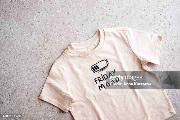 close-up of beige t-shirt with a print “friday mood” on light background, top view - shirt no people foto e immagini stock
