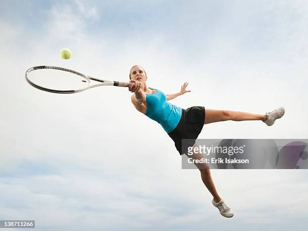 caucasian woman jumping in mid-air playing tennis - human arm stock pictures, royalty-free photos & images