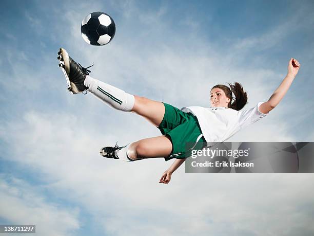 caucasian teenager kicking soccer ball in mid-air - girl kicking stock pictures, royalty-free photos & images