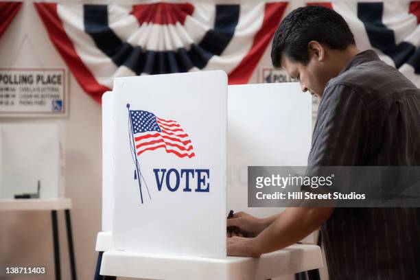mixed race voter voting in polling place - american voting booth stock pictures, royalty-free photos & images