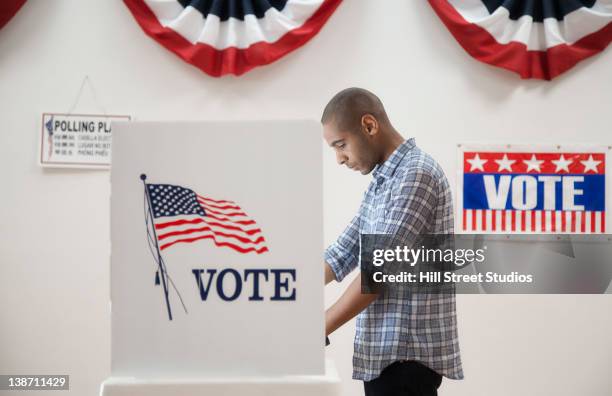 man voting in polling place - votar fotografías e imágenes de stock