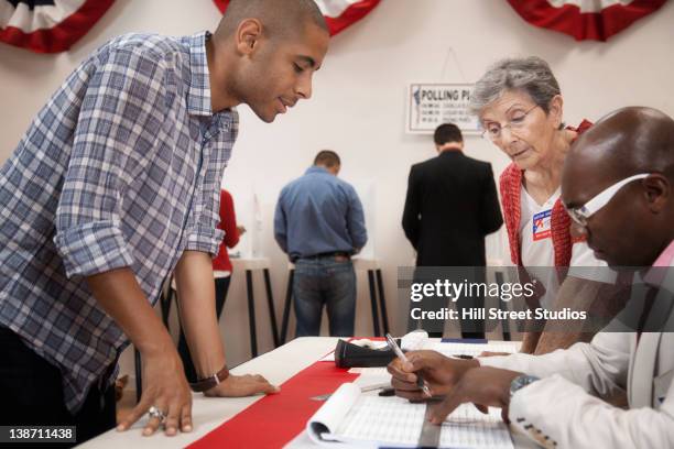 man arriving at registration desk in polling place - iscrizione nelle liste elettorali foto e immagini stock