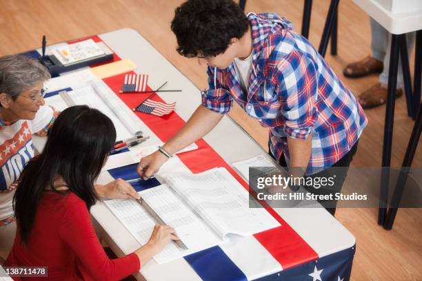 man arriving at registration desk in polling place - iscrizione nelle liste elettorali foto e immagini stock