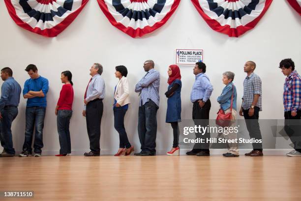 voters waiting to vote in polling place - stembureau stockfoto's en -beelden