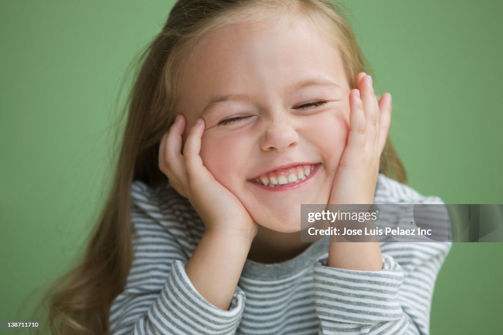 Grinning Caucasian girl with head in hands
