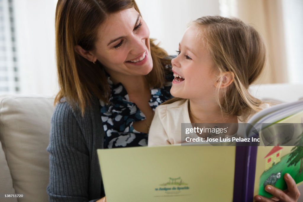 Caucasian mother reading book to daughter