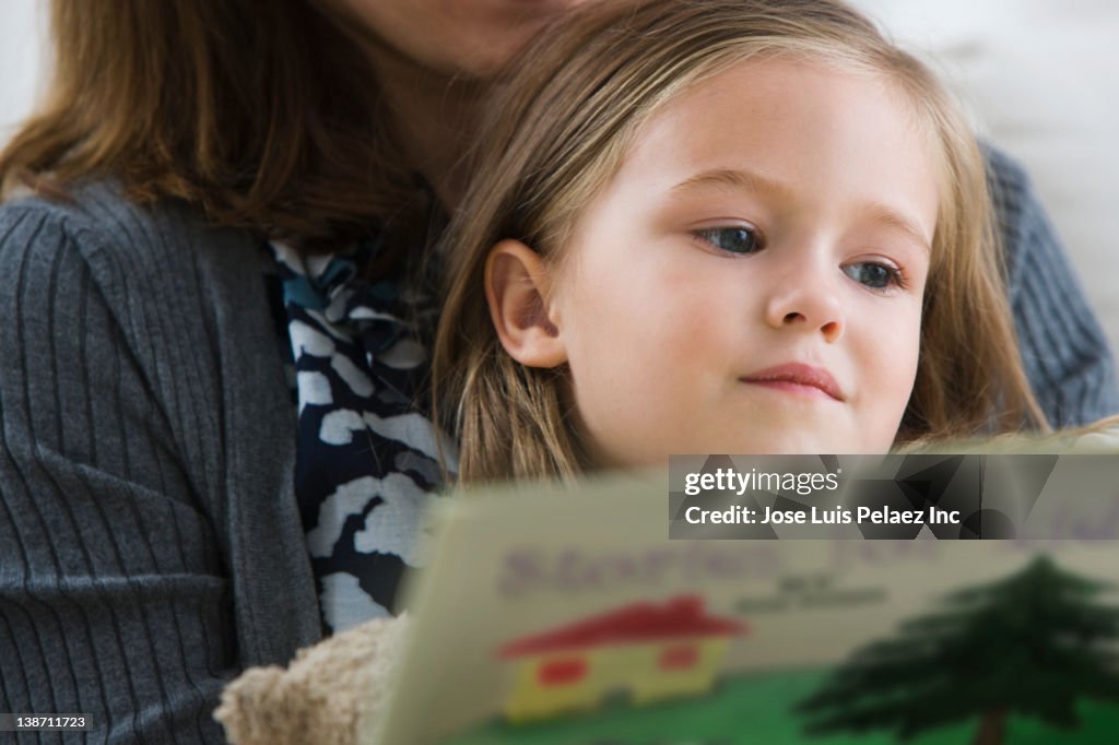 Caucasian mother reading book to daughter