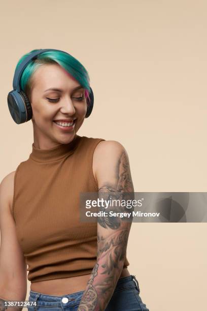 young attractive woman with green and pink hairs dancing with headphones - body piercings stock pictures, royalty-free photos & images