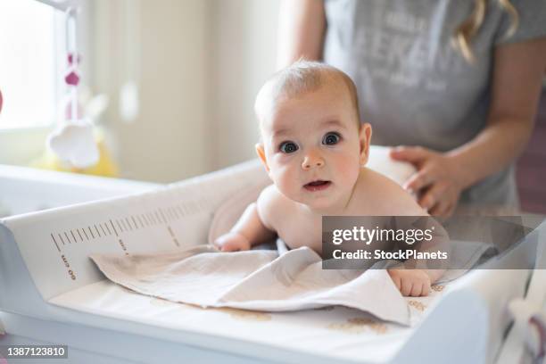 kleines mädchen in windel auf wickeltisch - baby diapers stock-fotos und bilder