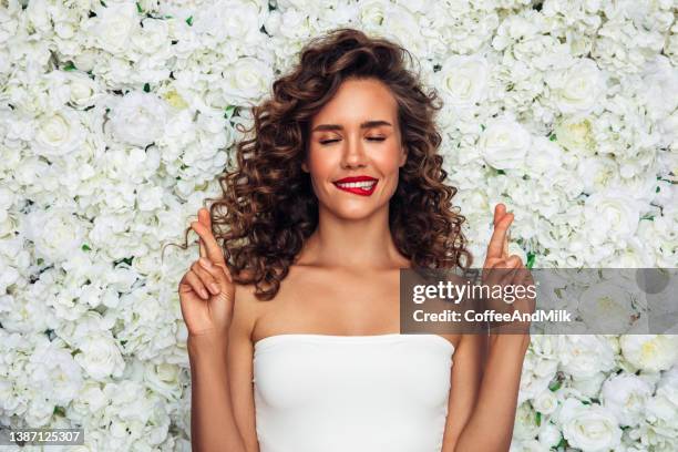 beautiful girl with a wall of flowers - fortune stock pictures, royalty-free photos & images