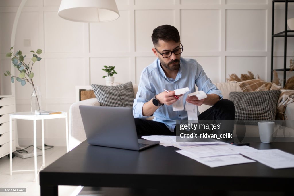 Businessman using calculator while going through financial bills.