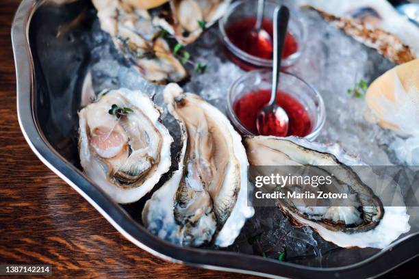 oysters are on a plate with ice and sauce - crustacean stockfoto's en -beelden