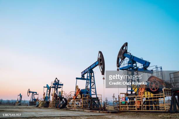 several oil pumps in blue color on a clear sky background, great for a copy space. - industria petrolchimica foto e immagini stock