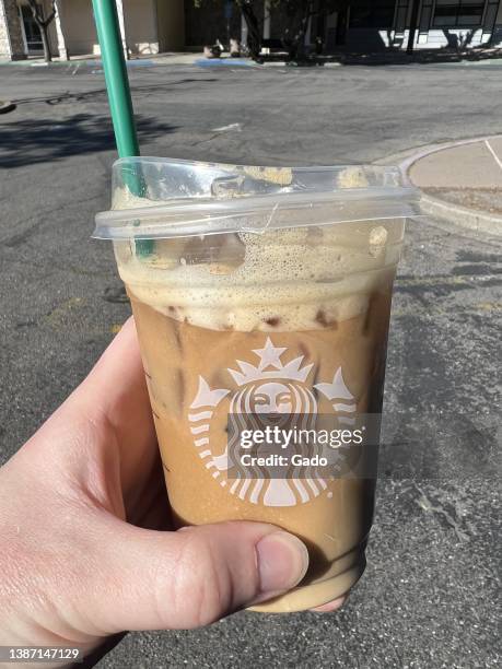 Person's hand holding new vegan, plant-based Toasted Vanilla Oatmilk Shaken Espresso drink at Starbucks, Moraga, California, March 6, 2022. Photo...