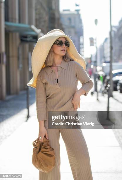 Amelie Stanescu is seen wearing beige Someday pants and polo, brown GIA Studios bag, floppy straw COS hat, Mango shoes, Burberry sunglasses during...