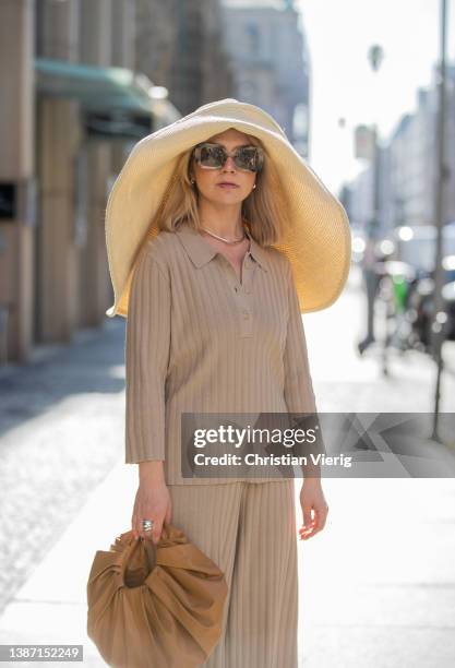 Amelie Stanescu is seen wearing beige Someday pants and polo, brown GIA Studios bag, floppy straw COS hat, Mango shoes, Burberry sunglasses during...