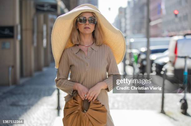 Amelie Stanescu is seen wearing beige Someday pants and polo, brown GIA Studios bag, floppy straw COS hat, Mango shoes, Burberry sunglasses during...