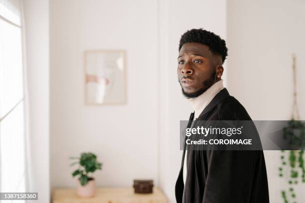 man looking away with a shocked expression on his face while standing at home. - daze stock-fotos und bilder