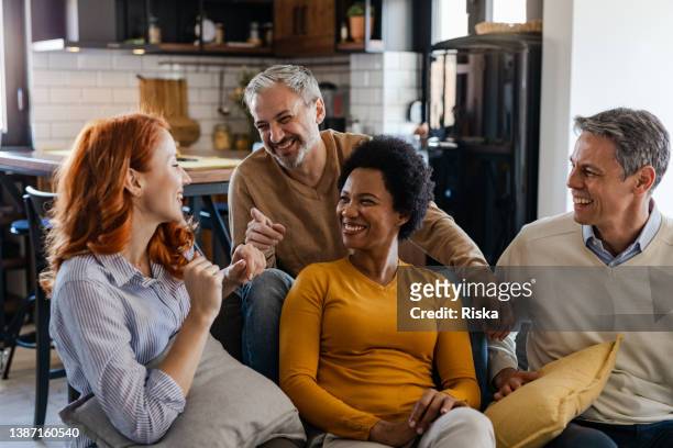 group of mid adult friends at home - reünie sociaal stockfoto's en -beelden