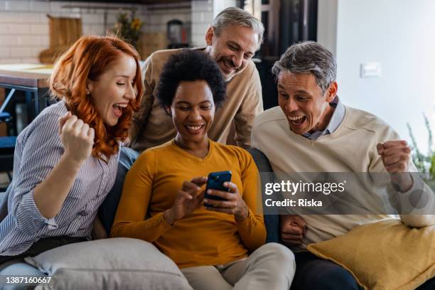 gruppe von freunden, die sich aufgeregt fühlen, während sie auf das telefon schauen - blessed stock-fotos und bilder