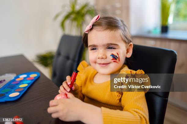 portrait of a cute little girl painting easter eggs - pintura em têmpera imagens e fotografias de stock