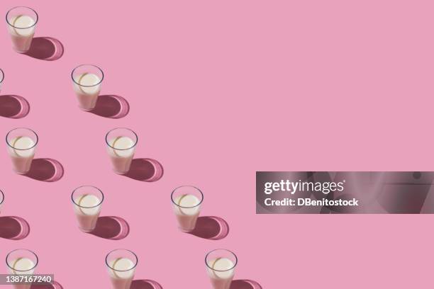 pattern of glass cups filled with milk in hard light, on the left side, on pink background. dairy, shortage, calcium, grow and drink concept - lactic acid stock pictures, royalty-free photos & images