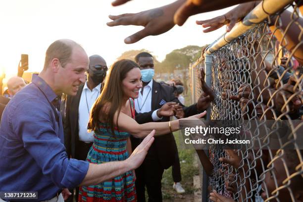 Prince William, Duke of Cambridge and Catherine, Duchess of Cambridge shake hands with children during a visit to Trench Town, the birthplace of...