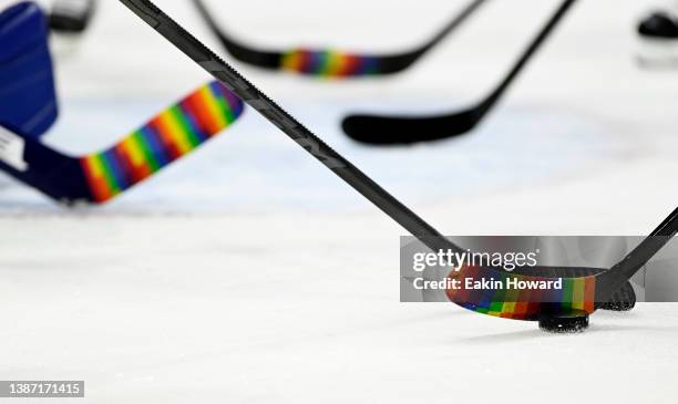 Tampa Bay Lightning players warm up with sticks wrapped in rainbows for pride night before a game against the Carolina Hurricanes at PNC Arena on...