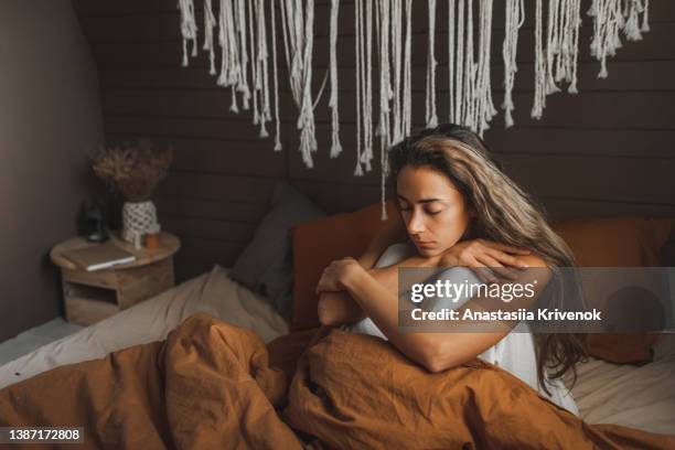 young sadness woman sitting on bed at home. - dark room foto e immagini stock