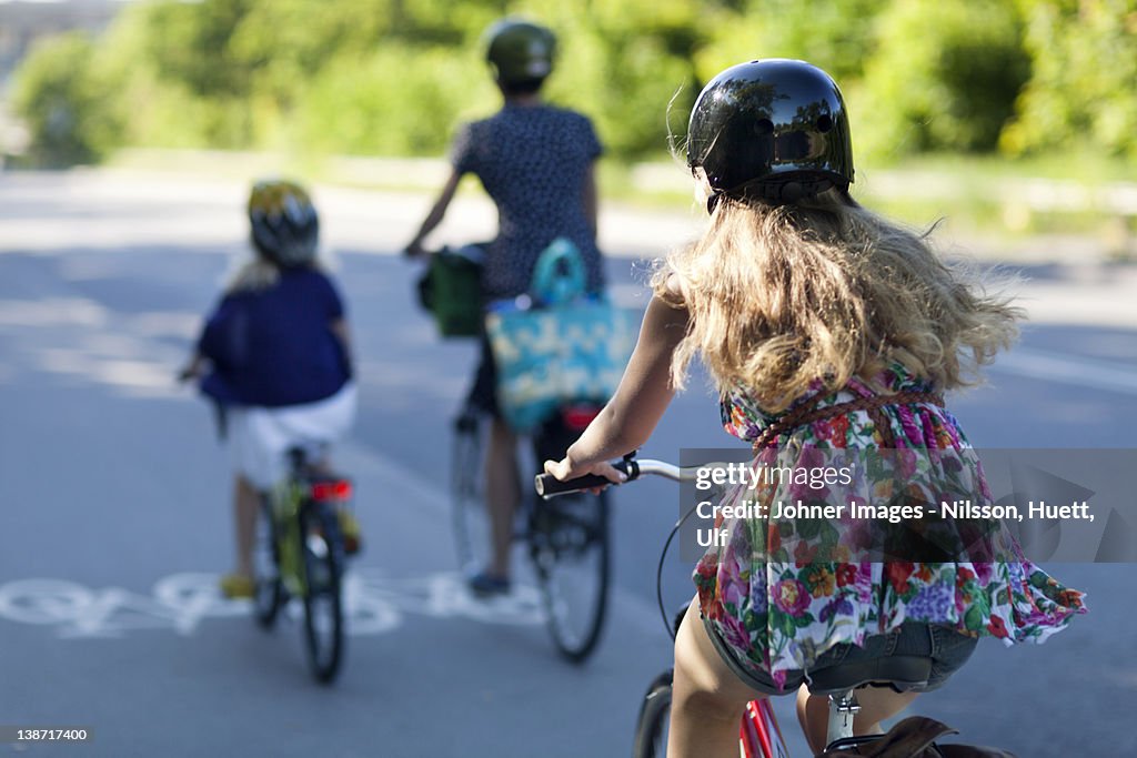 A woman and two children riding bikes