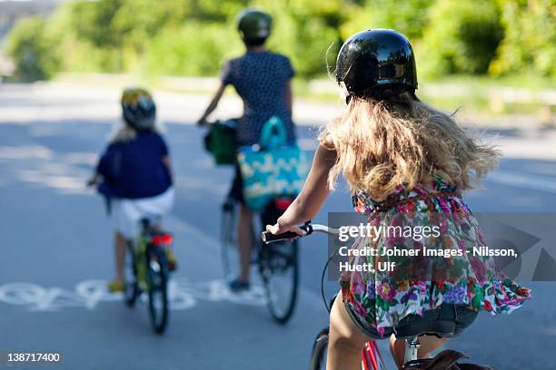 a woman and two children riding bikes - teenager cycling helmet stock pictures, royalty-free photos & images