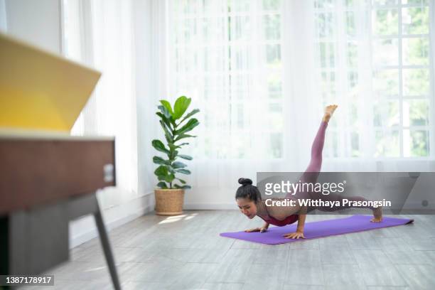 beautiful brunette fitness woman make stretching exercises indoors at home - virtual coach stock pictures, royalty-free photos & images