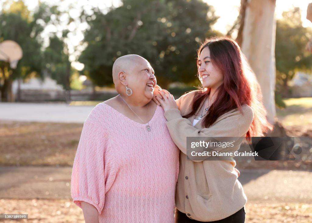 Mother fighting cancer hugging child in park