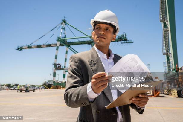 latin american male international trade agent analyzing data while holding clipboard - funcionário de alfândega imagens e fotografias de stock