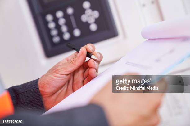 asian american male supervisor taking notes on clipboard after setting reefer container temperature - customs agent stock pictures, royalty-free photos & images