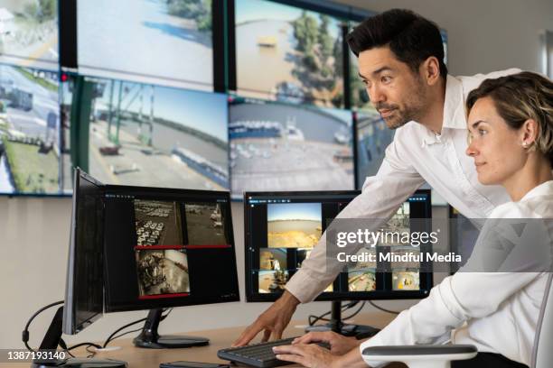 male and female security coworkers watching monitors at control room - övervakningskamera bildbanksfoton och bilder