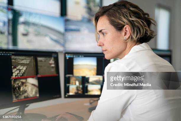adult female security guard looking carefully at computer screen - responsibility stockfoto's en -beelden